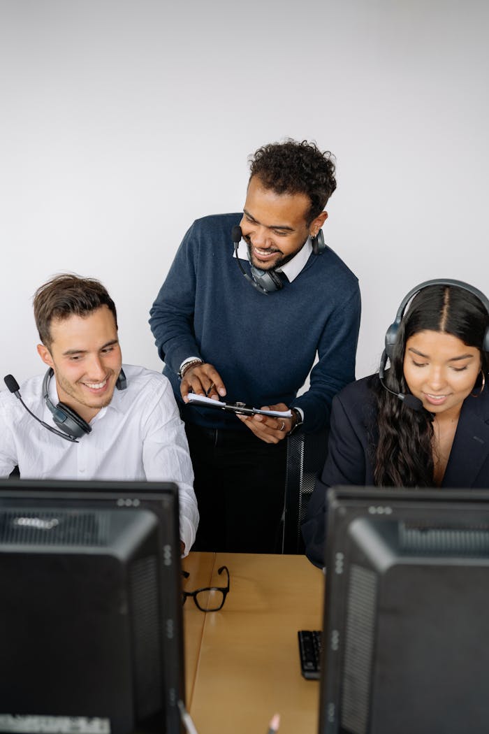 A diverse group of call center agents collaborating, wearing headsets, and using computers.